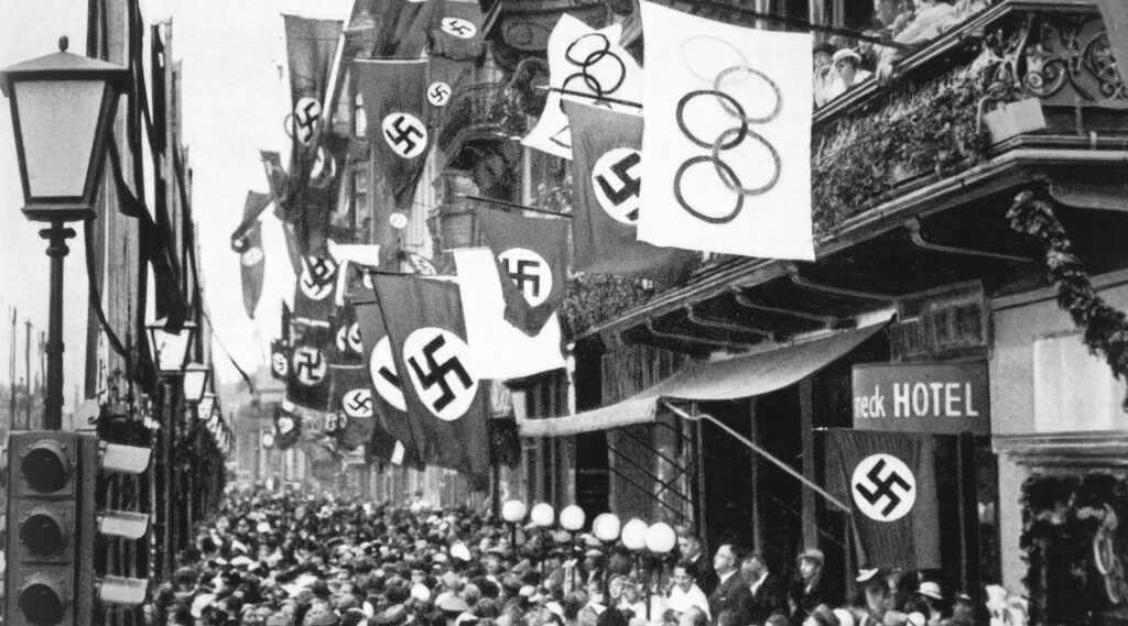 Crowd on a street with Olympics and Nazi flags