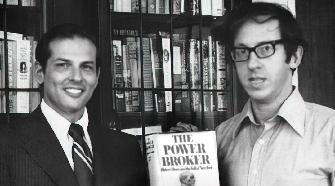 Two men standing by a bookcase