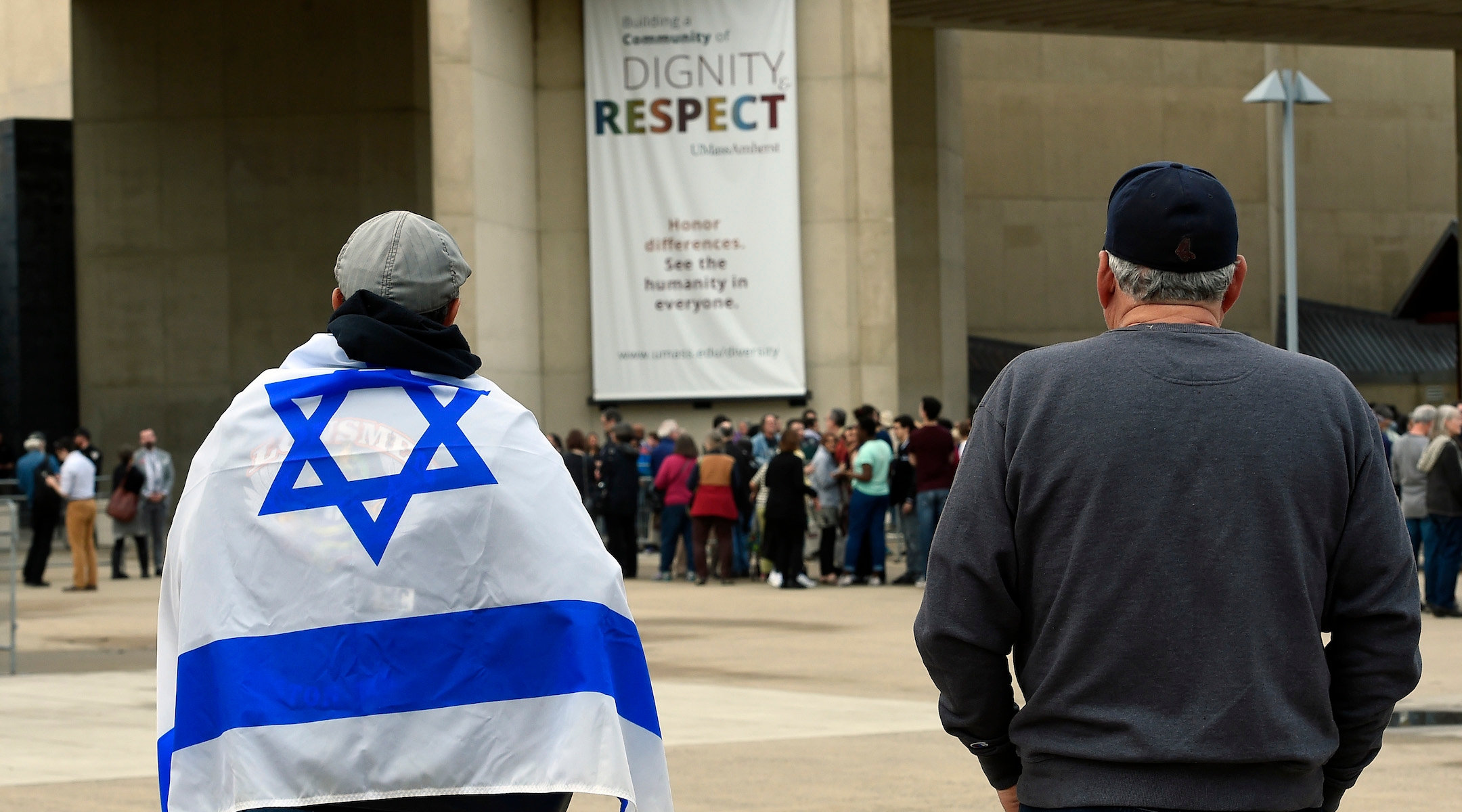 Two men, one in an Israeli flag, face a crowd