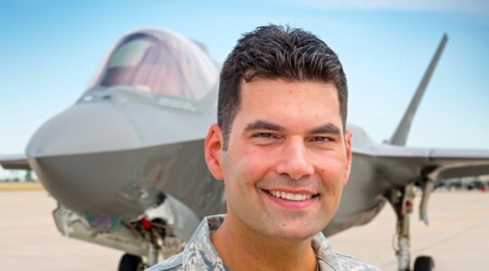 A candidate posing in front of a fighter jet