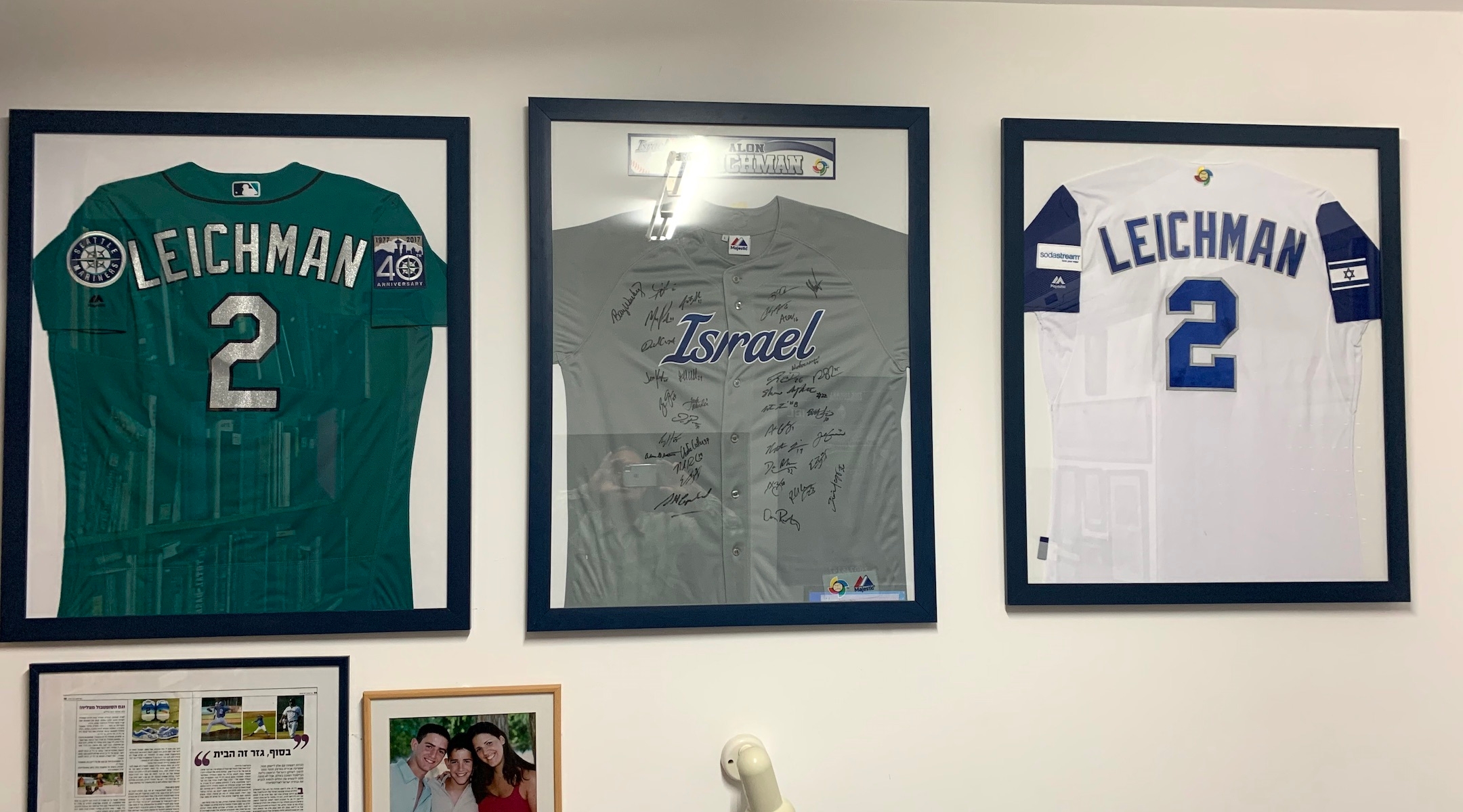 Various jerseys from Alon Leichman’s baseball career are displayed on the wall of his family’s home at Kibbutz Gezer, Israel. (Elli Wohlgelernter)