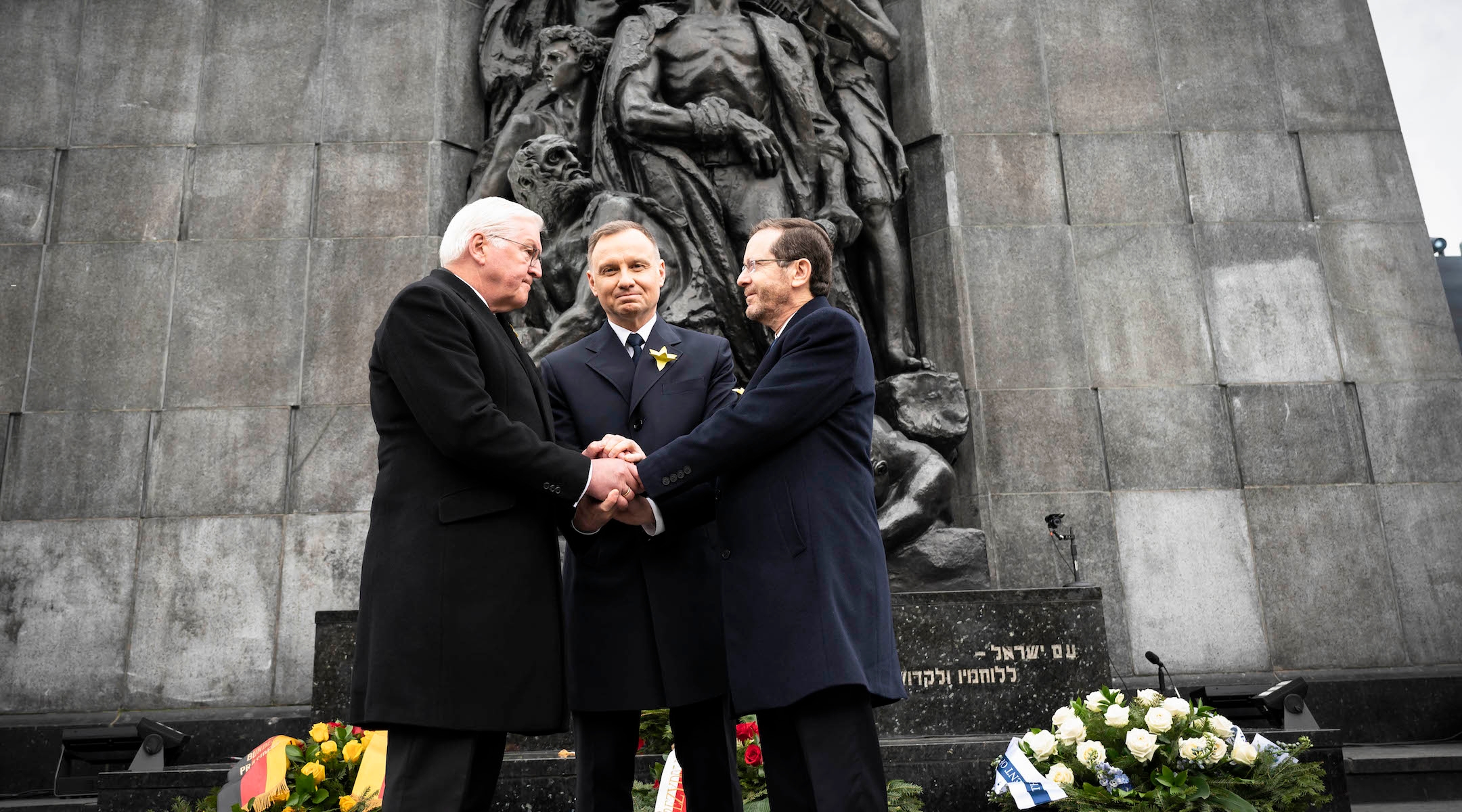 From left to right: German President Frank-Walter Steinmeier, Polish President Andrzej Duda and Israeli President Issac Herzog hold hands before the 80th anniversary commemoration of the Warsaw Ghetto Uprising, in front of the city’s Monument to the Ghetto Heroes, April 19, 2023. (German Government Press Office/Getty Images)