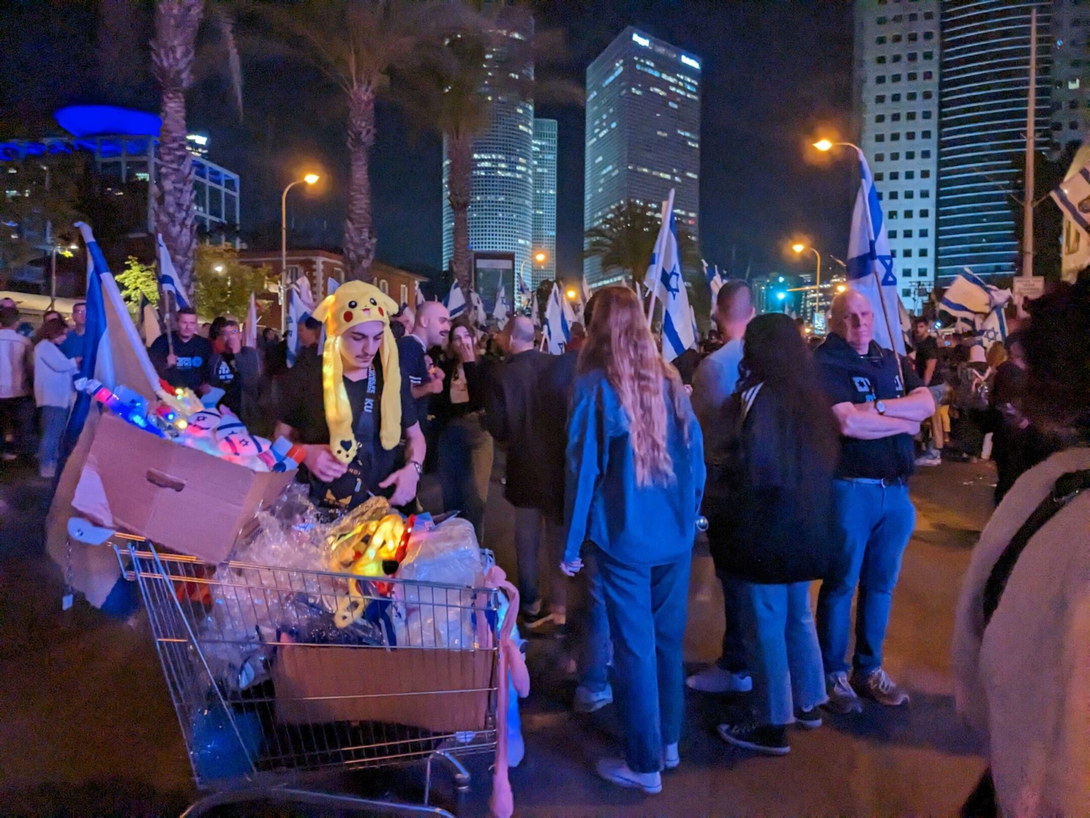 A flag vendor stands with his wares during a Yom Haatzmaut celebration and anti-government protest in Tel Aviv, April 25, 2023. (Ben Sales)