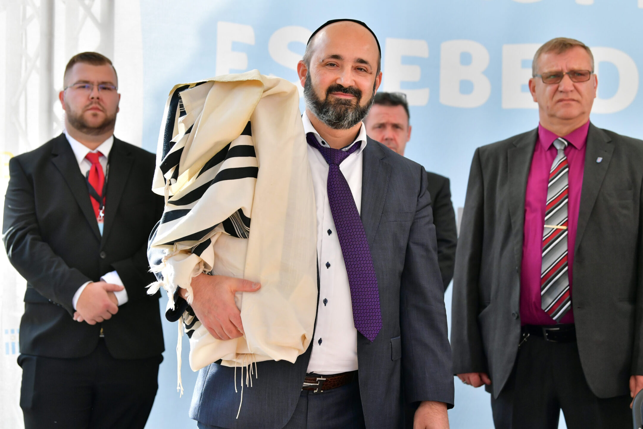 Rabbi Reuven Yaacobov stands on stage with security guards during the ceremonial handover of a new Torah scroll that he had written to the Jewish regional congregation in Erfurt, Germany, Sept. 30, 2021.(Martin Schutt/picture alliance via Getty Images)