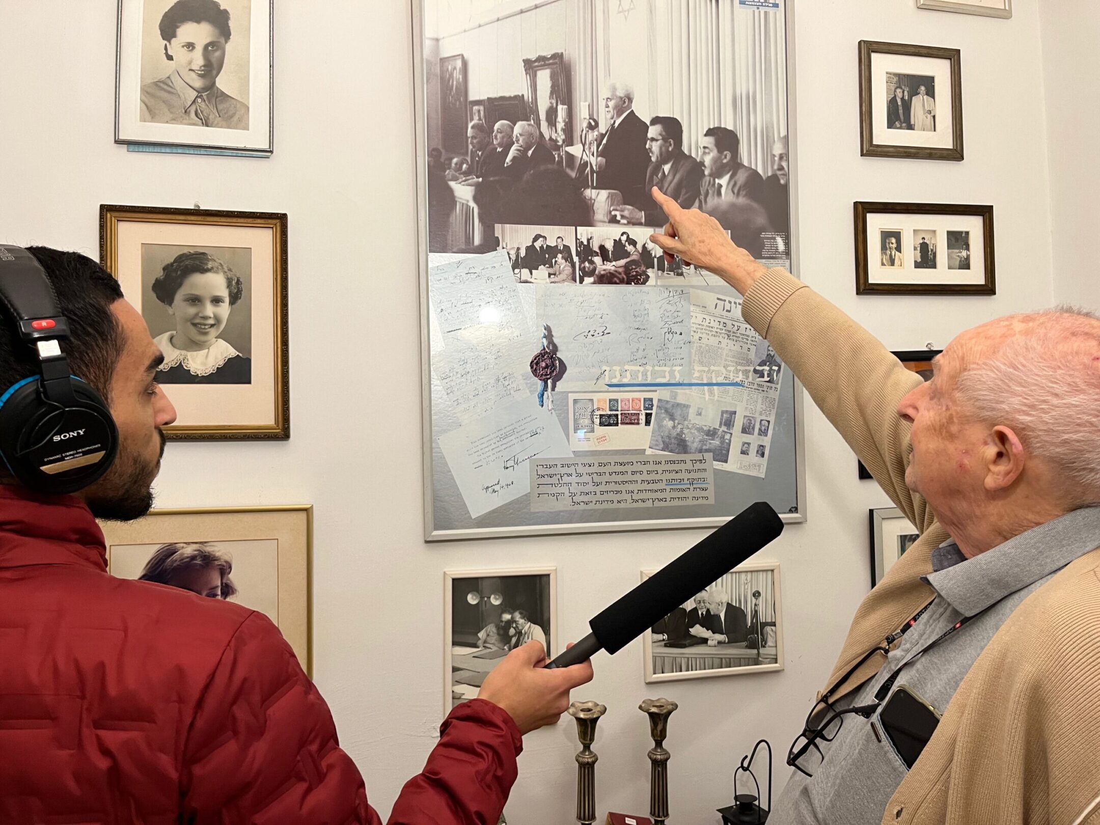 Moshe Inbar, the son of Peretz Bernstein, a signatory of Israel’s Declaration of Independence, points to his father in a picture from the signing ceremony, while “Israel Story” producer Jamal Risheq records him. (Courtesy “Israel Story”)