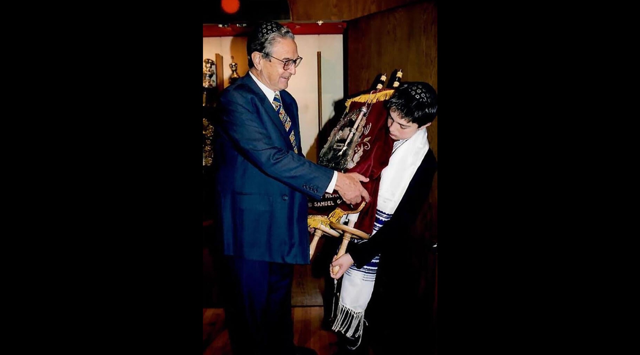 An undated photo of George Soros handing his son Alex a Torah scroll at his bar mitzvah. (Courtesy of the Soros family)