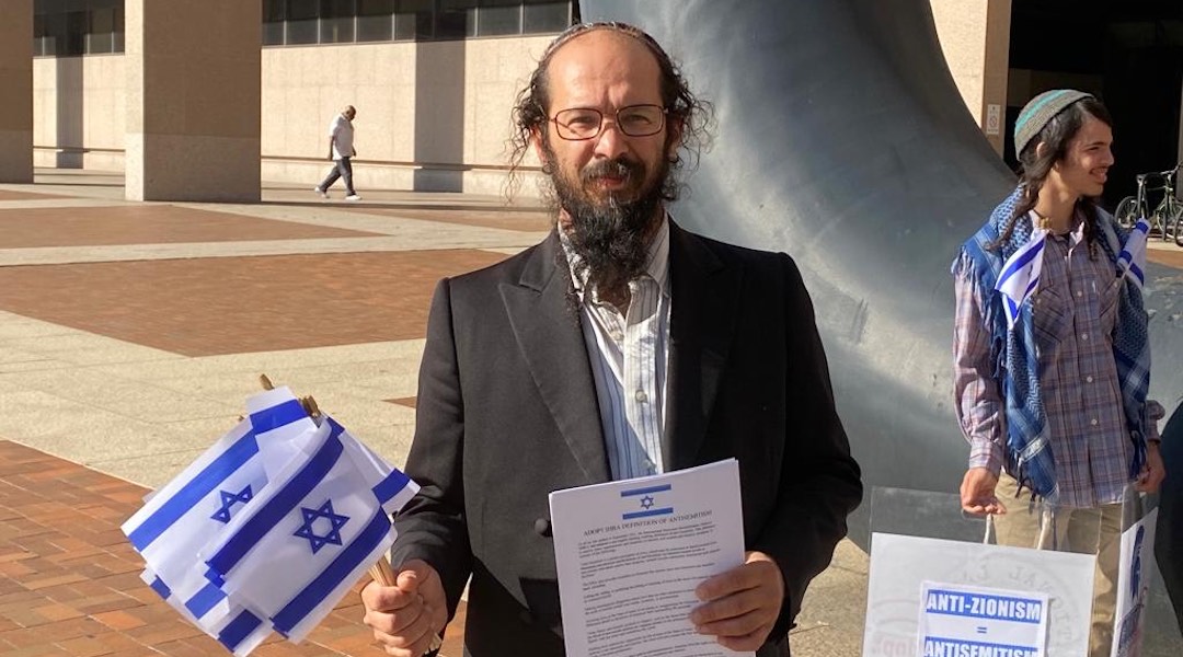 A rabbi outside a courthouse with Israeli flags