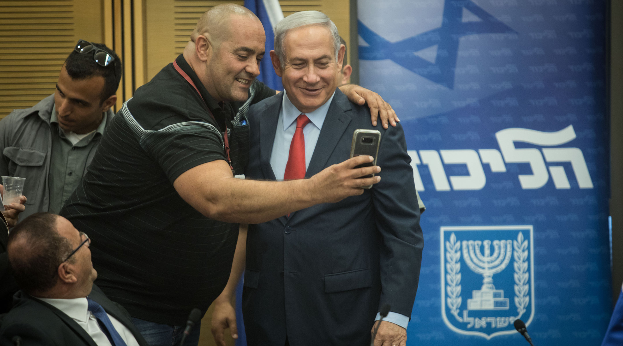 Prime Minister Benjamin Netanyahu poses for a selfie with Itzik Zarka, a Likud activist, during a Likud Party faction meeting at the Knesset, Israel's parliament, on July 9, 2018. (Hadas Parush/Flash90)
