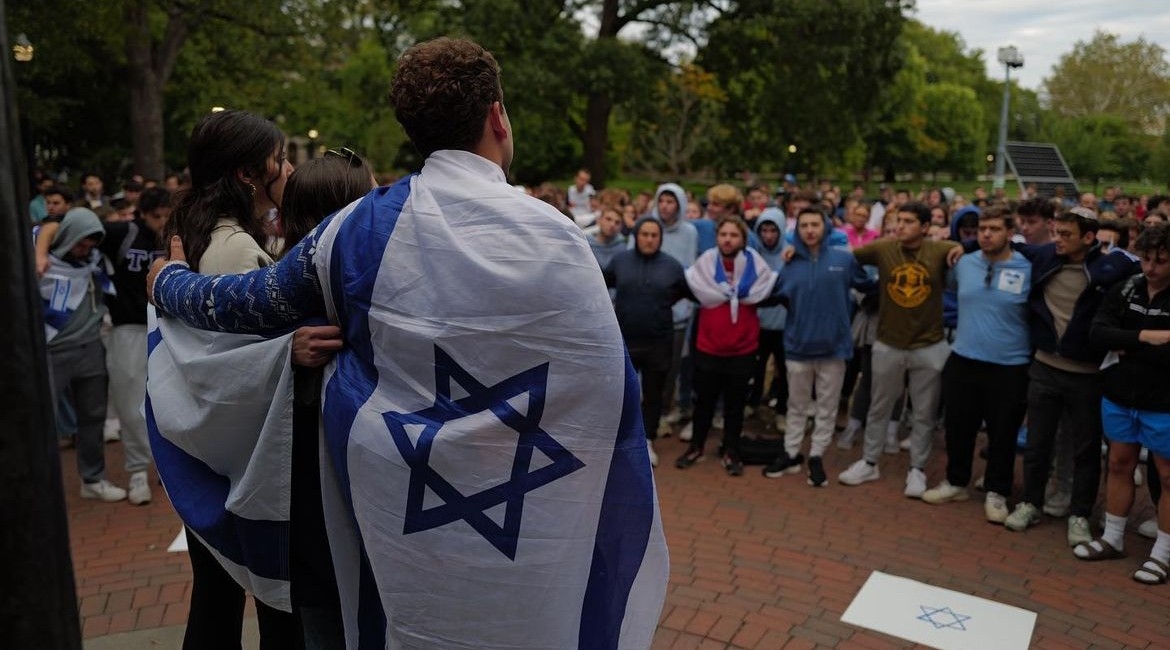 A student draped in an Israel flag addresses a crowd