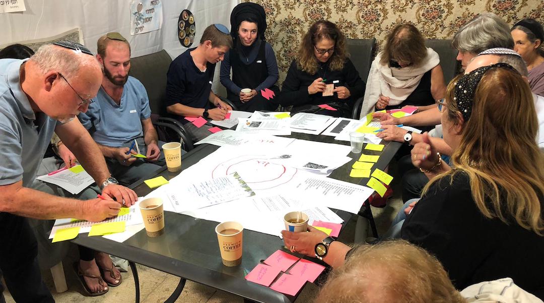 Participants complete an exercise during a dialogue session at a sukkah. (Courtesy of SOS Home)