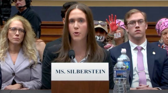 A woman testifies before the U.S. House as pro-Palestinian protesters sit behind her