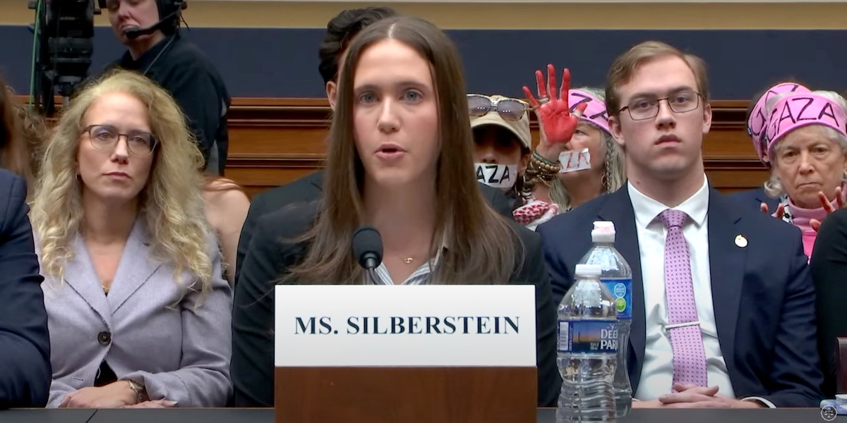 A woman testifies before the U.S. House as pro-Palestinian protesters sit behind her