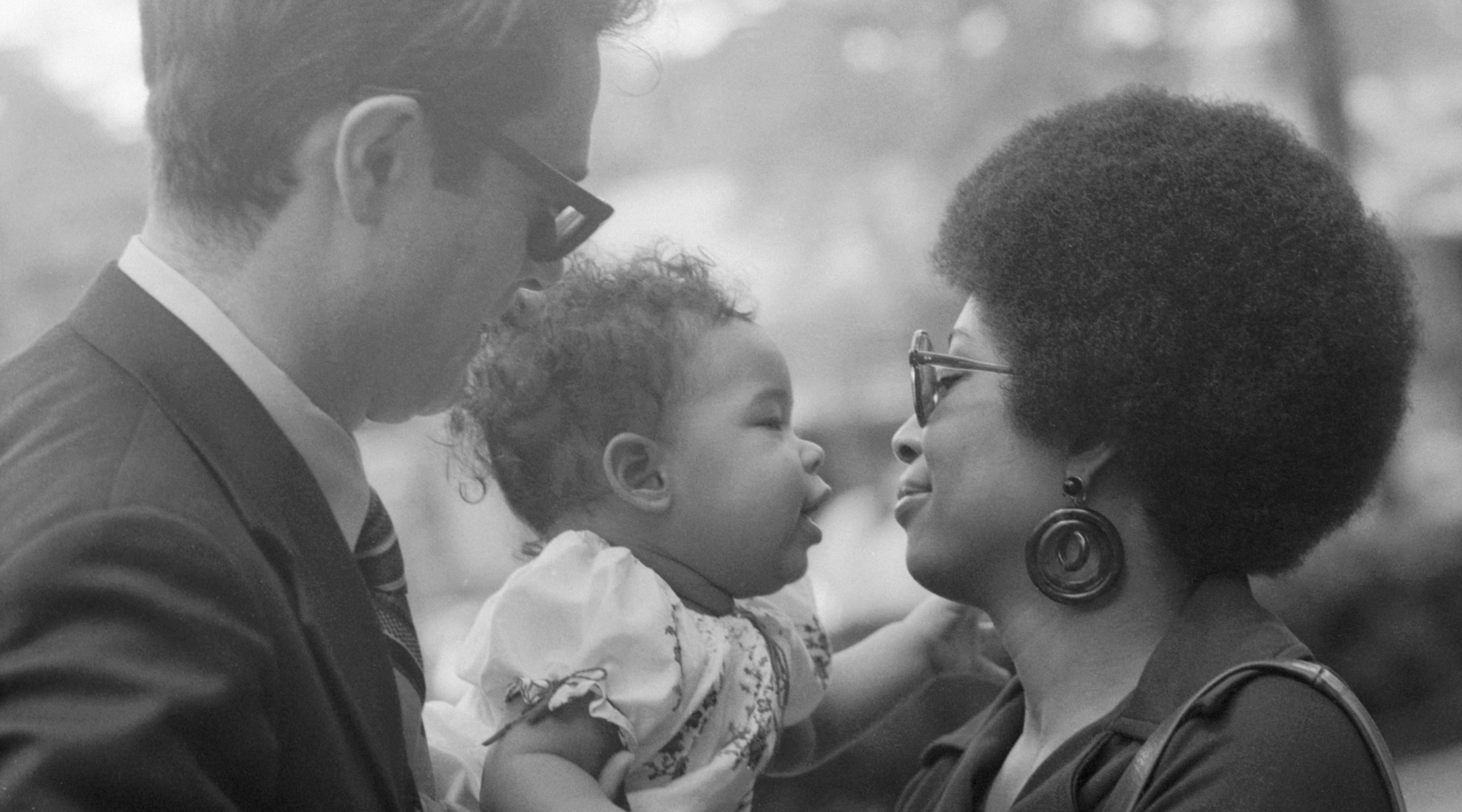 An interracial couple with their infant daughter in a black-and-white photograph from 1970
