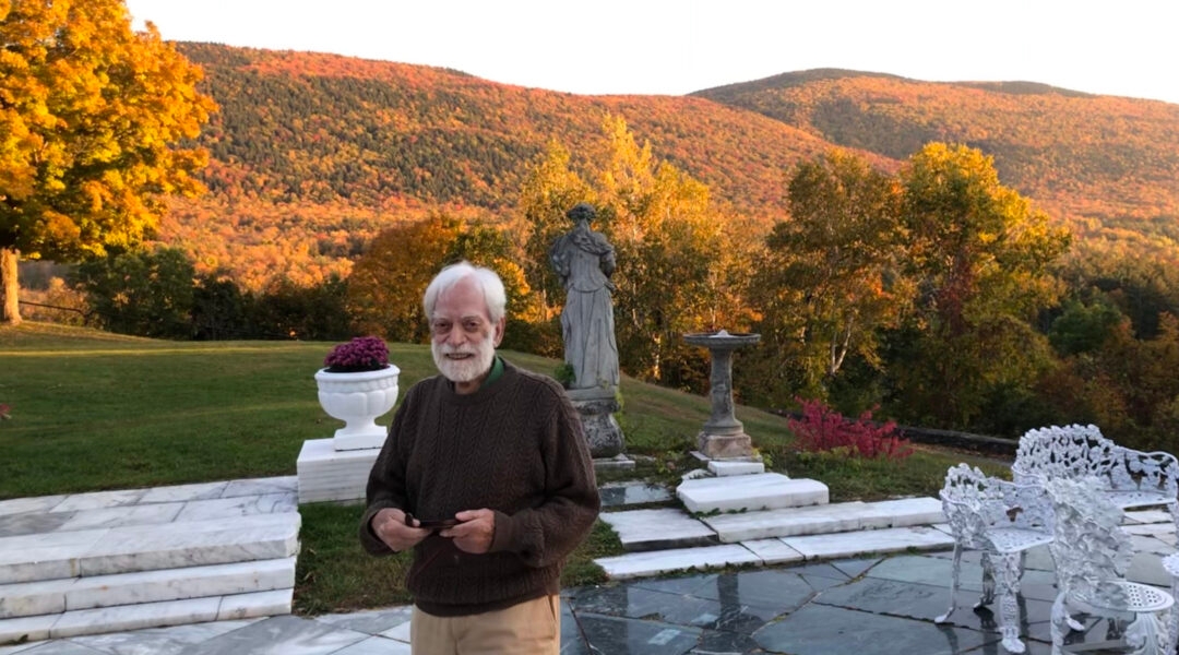 A smiling elderly man overlooking Vermont foliage in the fall