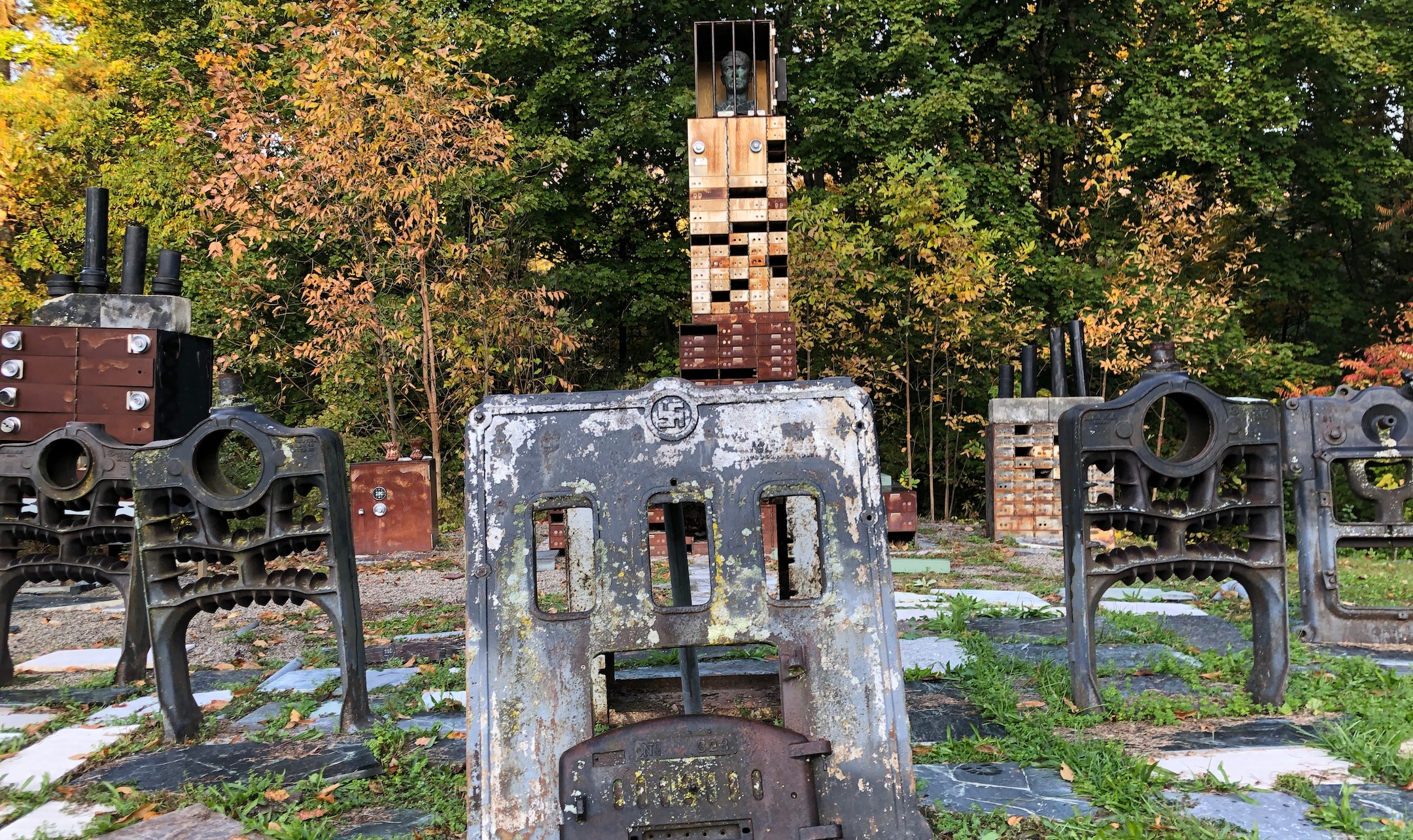 A modern-art sculpture of various metallic parts, some with a swastika on them, topped with a bust of Hitler