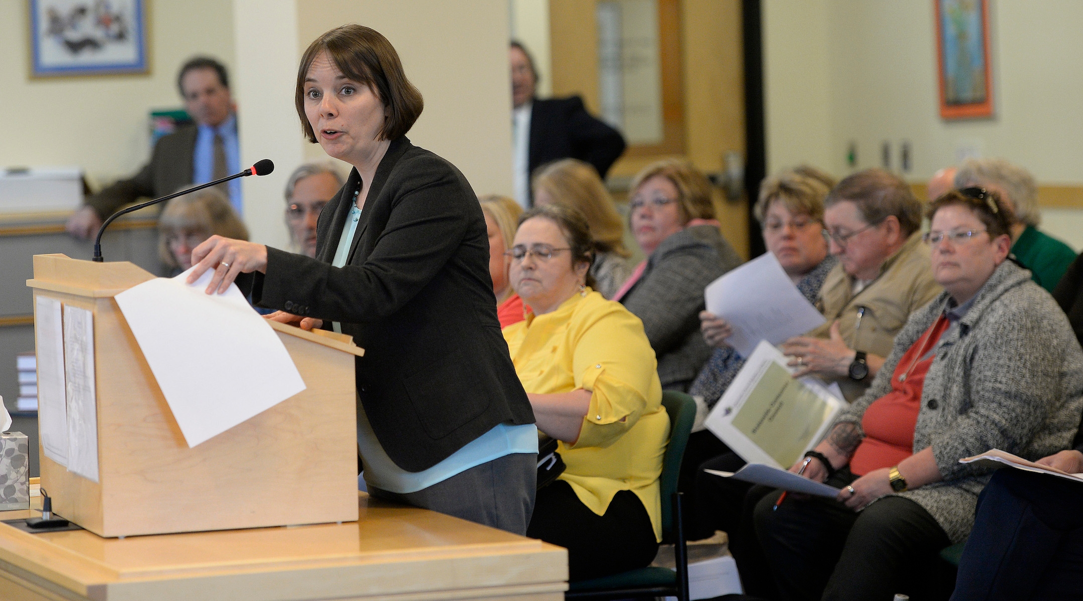 A politician speaks at a podium at a state house hearing in Maine