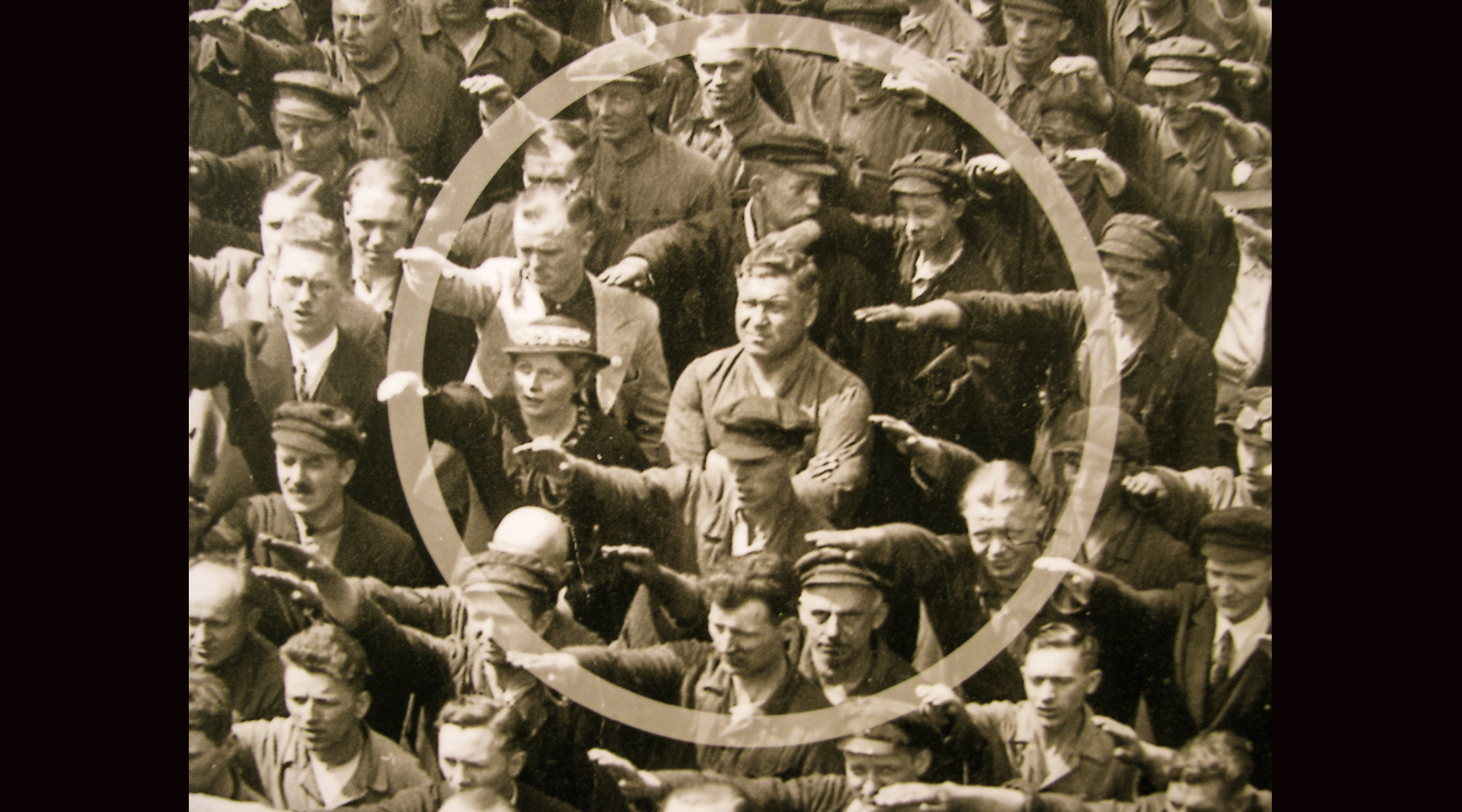 A photo of German ship workers giving a "Heil Hitler" salute in 1936, with one man standing with his arms folded, circled in the middle.