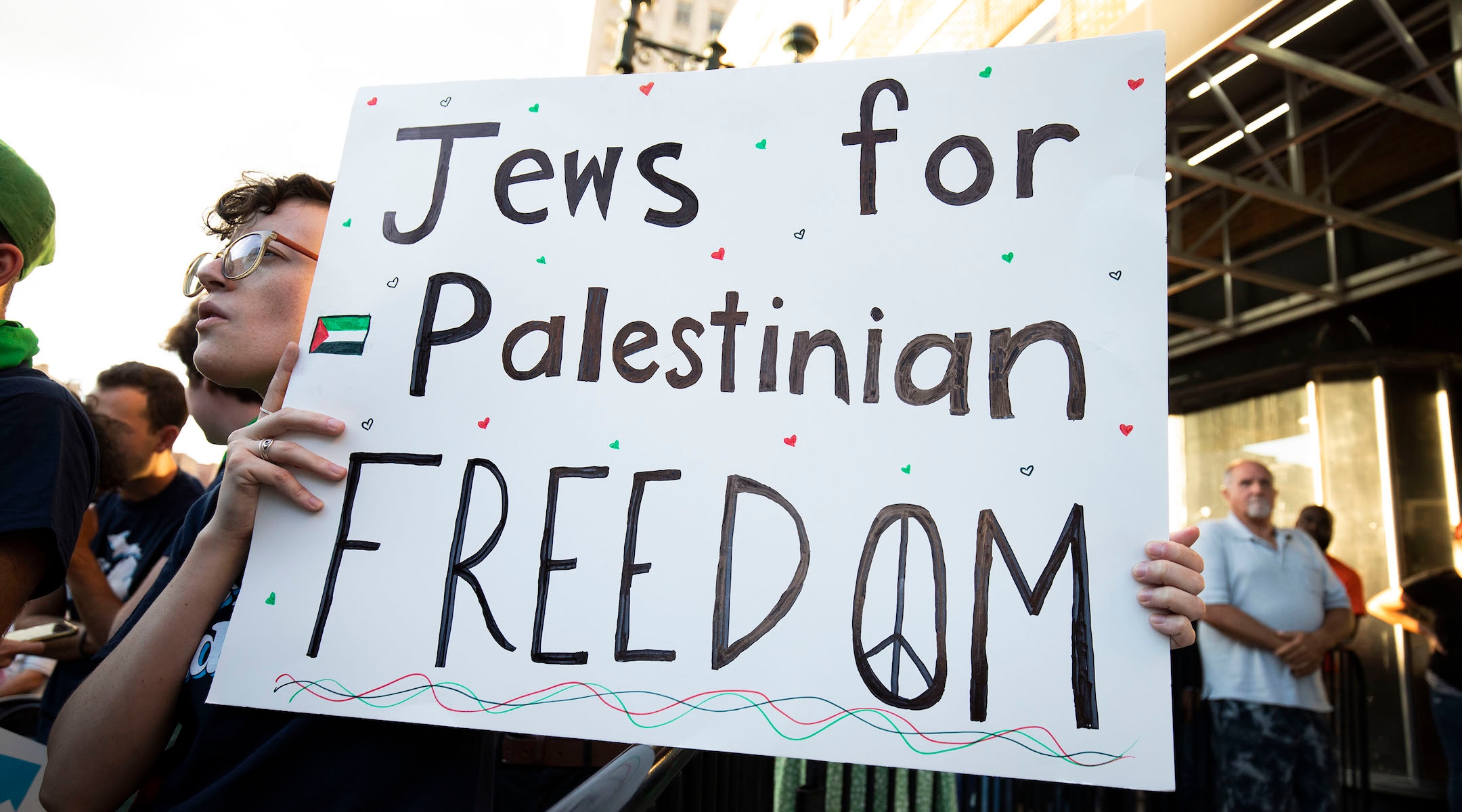 An attendee at a campaign rally holding a sign reading "Jews for Palestinian Freedom"