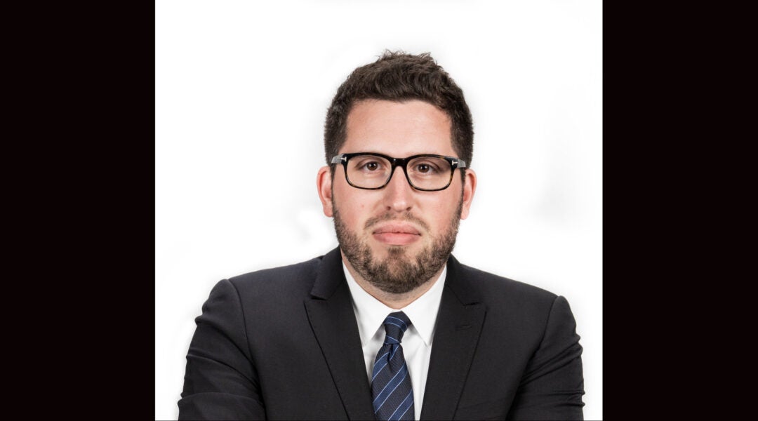 A headshot of a man wearing a suit and tie