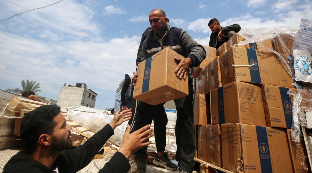 A Palestinian man hands off a box of aid in Gaza