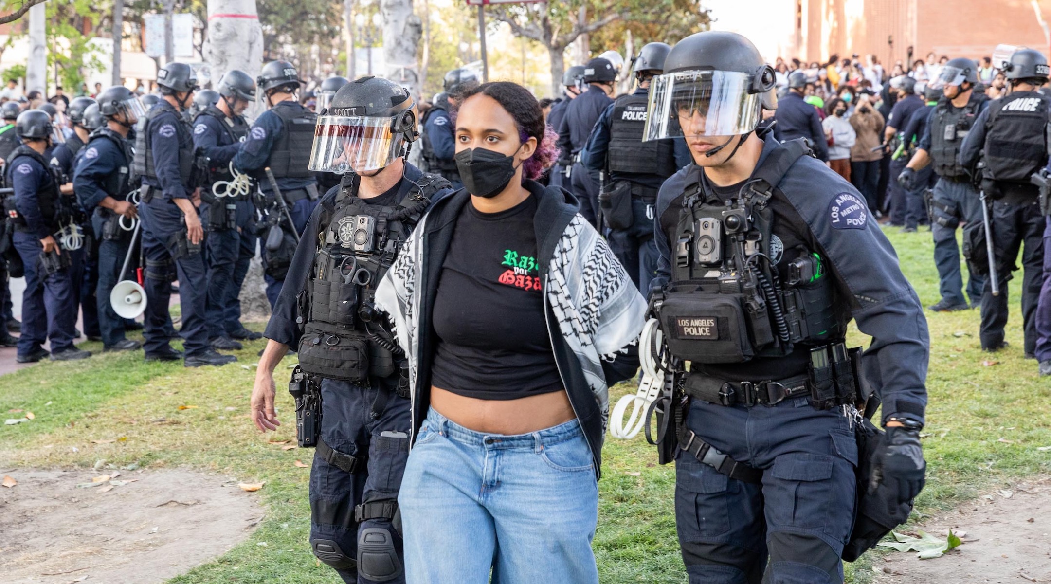 Police leading away a student wearing a pro-Palestinian shirt