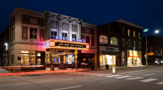 The exterior of a movie theater with lights lit up at night