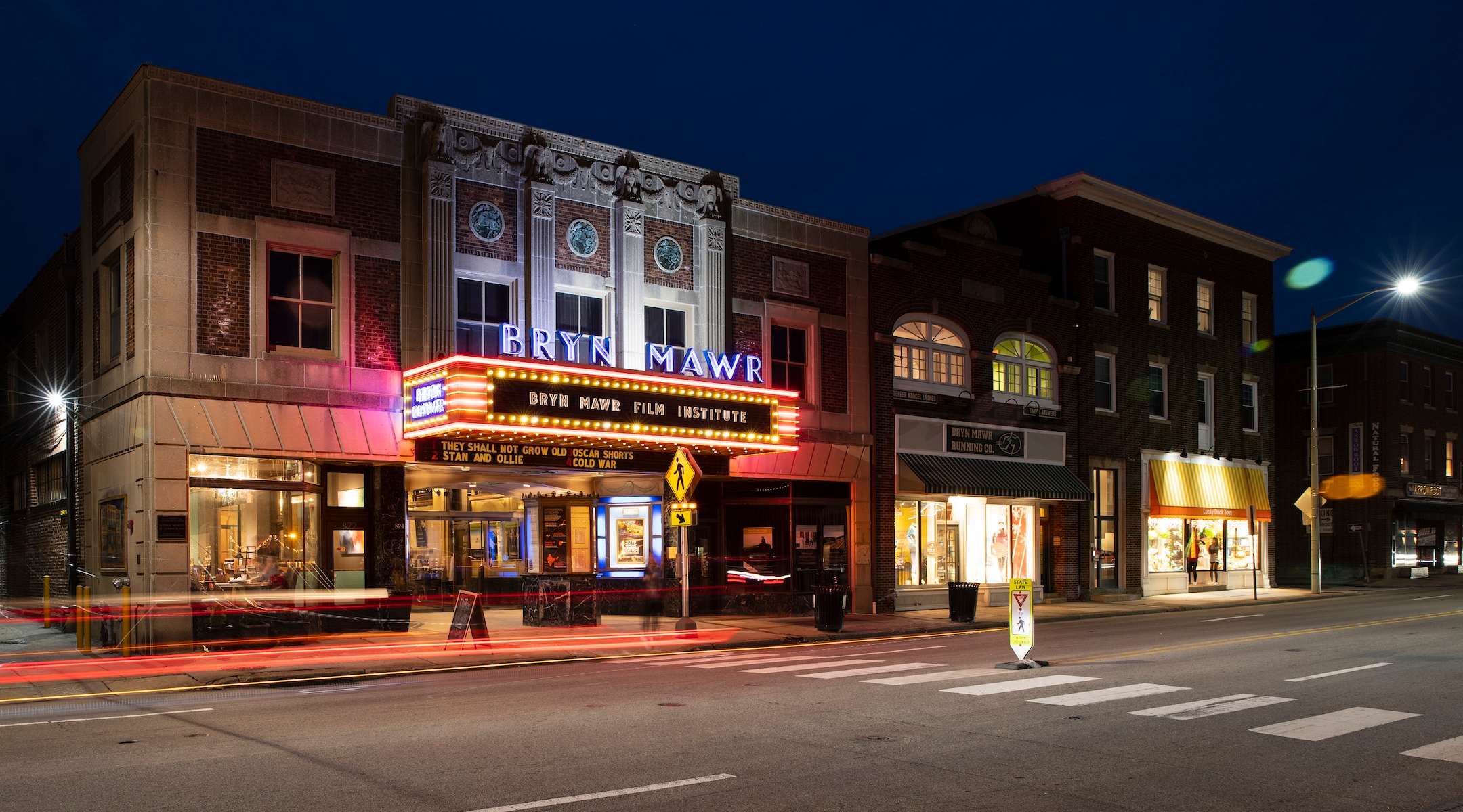 The exterior of a movie theater with lights lit up at night