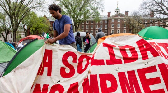 A student folds up a large banner reading "Gaza Solidarity Encampment"