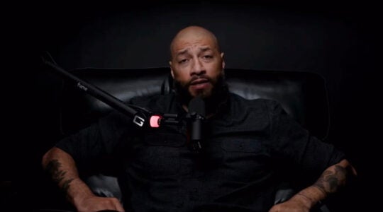 A man records a podcast with a black background