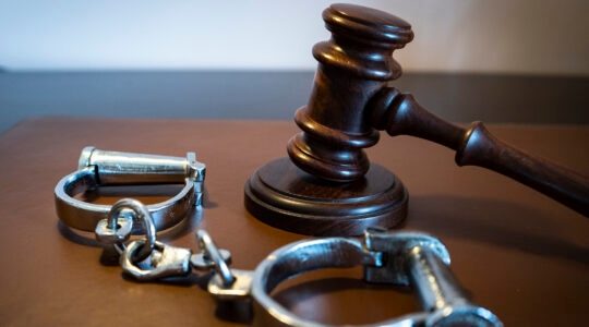 Gavel and handcuffs on a leather surface. (David Talukdar/Getty Images)