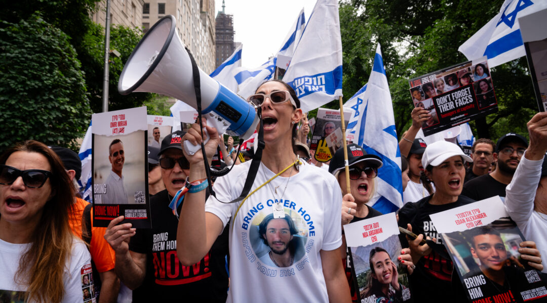 A relative of a hostage holds a megaphone at Sunday's Israel parade. Calling for the release of the hostages held in Gaza was a focus of this year's parade. (Luke Tress)