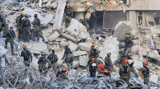 Uniformed workers inspect the rubble of an apartment building after an Iranian missile strike in Bat Yam, Israel on June 2025.