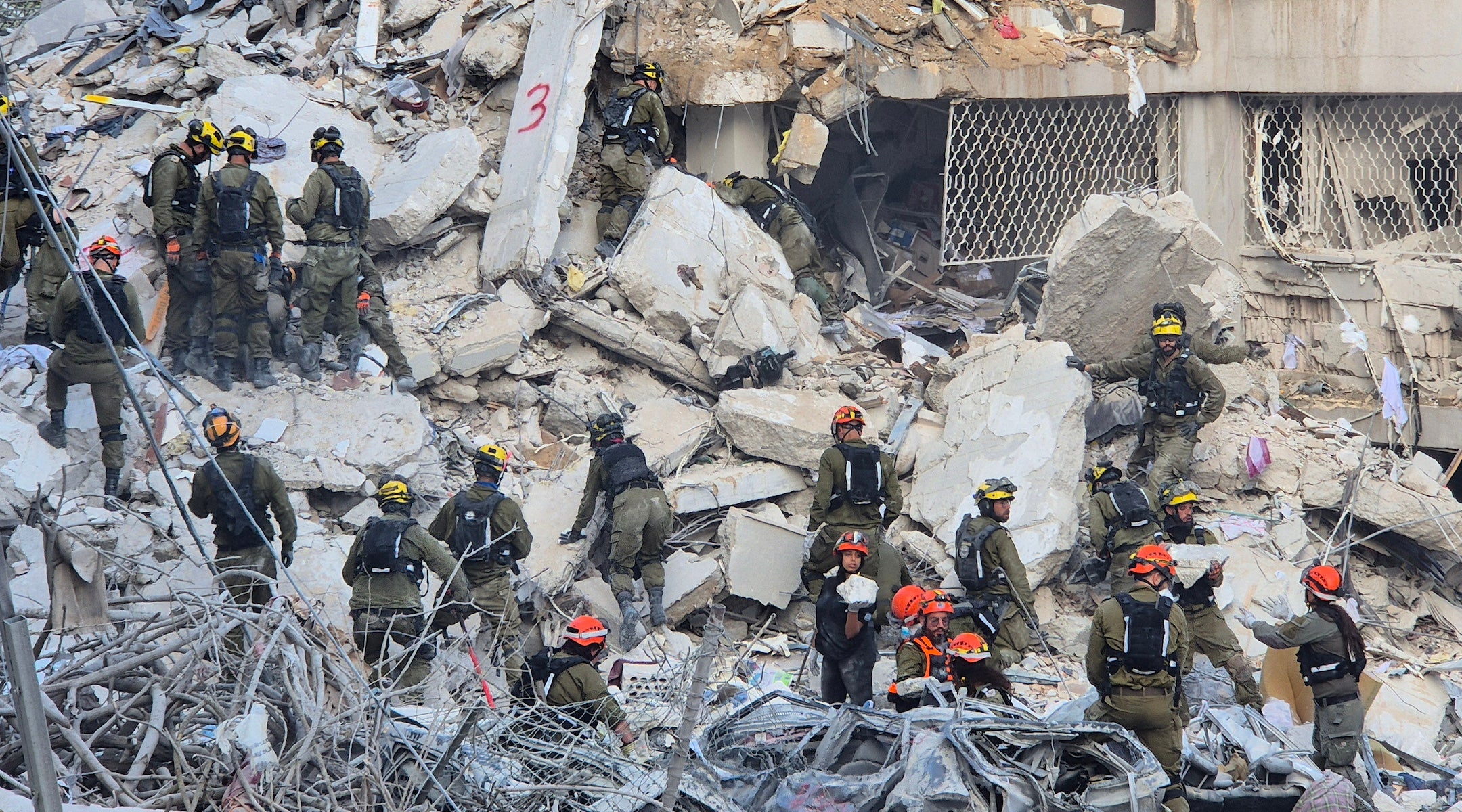 Uniformed workers inspect the rubble of an apartment building after an Iranian missile strike in Bat Yam, Israel on June 2025.