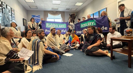 A group of rabbis sit and stand in Sen. John Thunes office, holding banners that read "Rabbis say: Protect Life!” and “Rabbis say: Stop the Blockade."