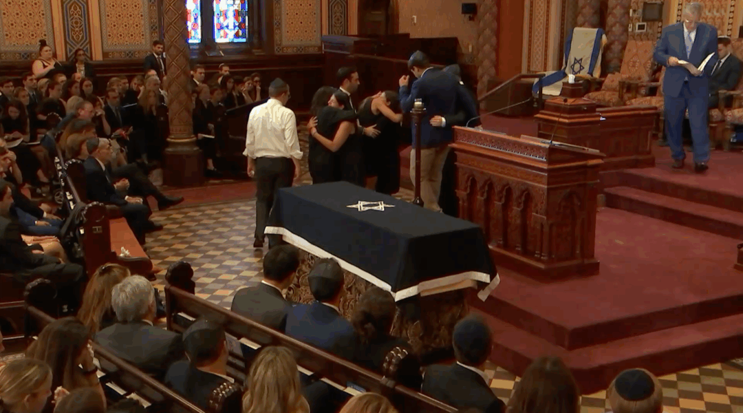 Family and friends of Julia Hyman hug during her funeral