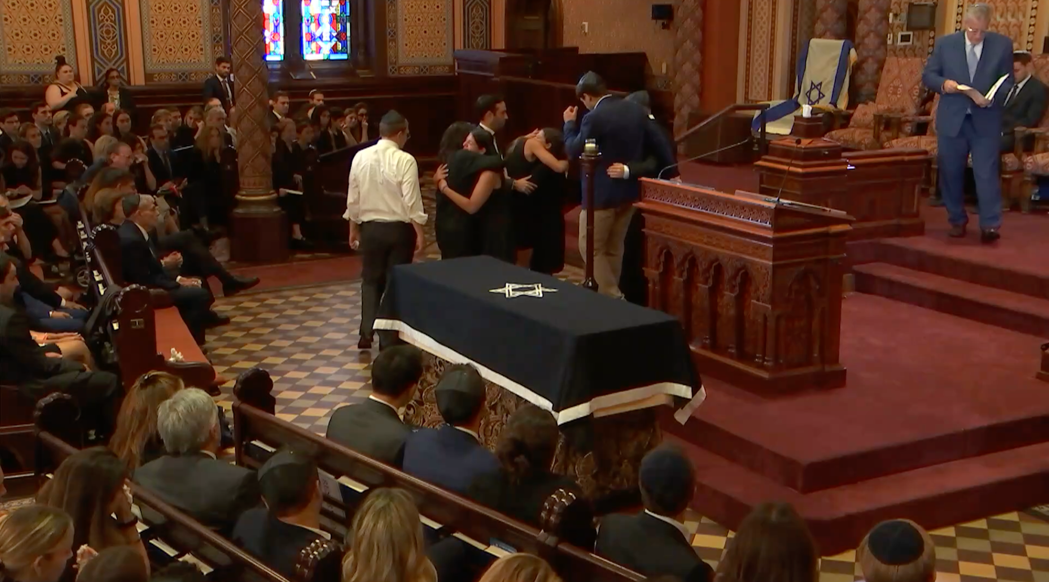 Family and friends of Julia Hyman hug during her funeral