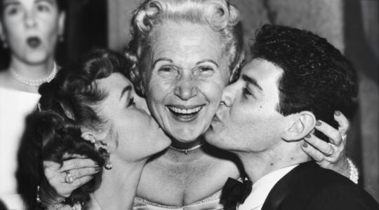 Jennie Grossinger, proprietor of Grossinger's Catksills Resort, is flanked by Debbie Reynolds and Eddie Fisher, who are both kissing her on her cheeks