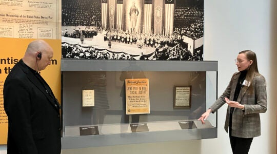 A bishop studies a glass case in a Holocaust museum