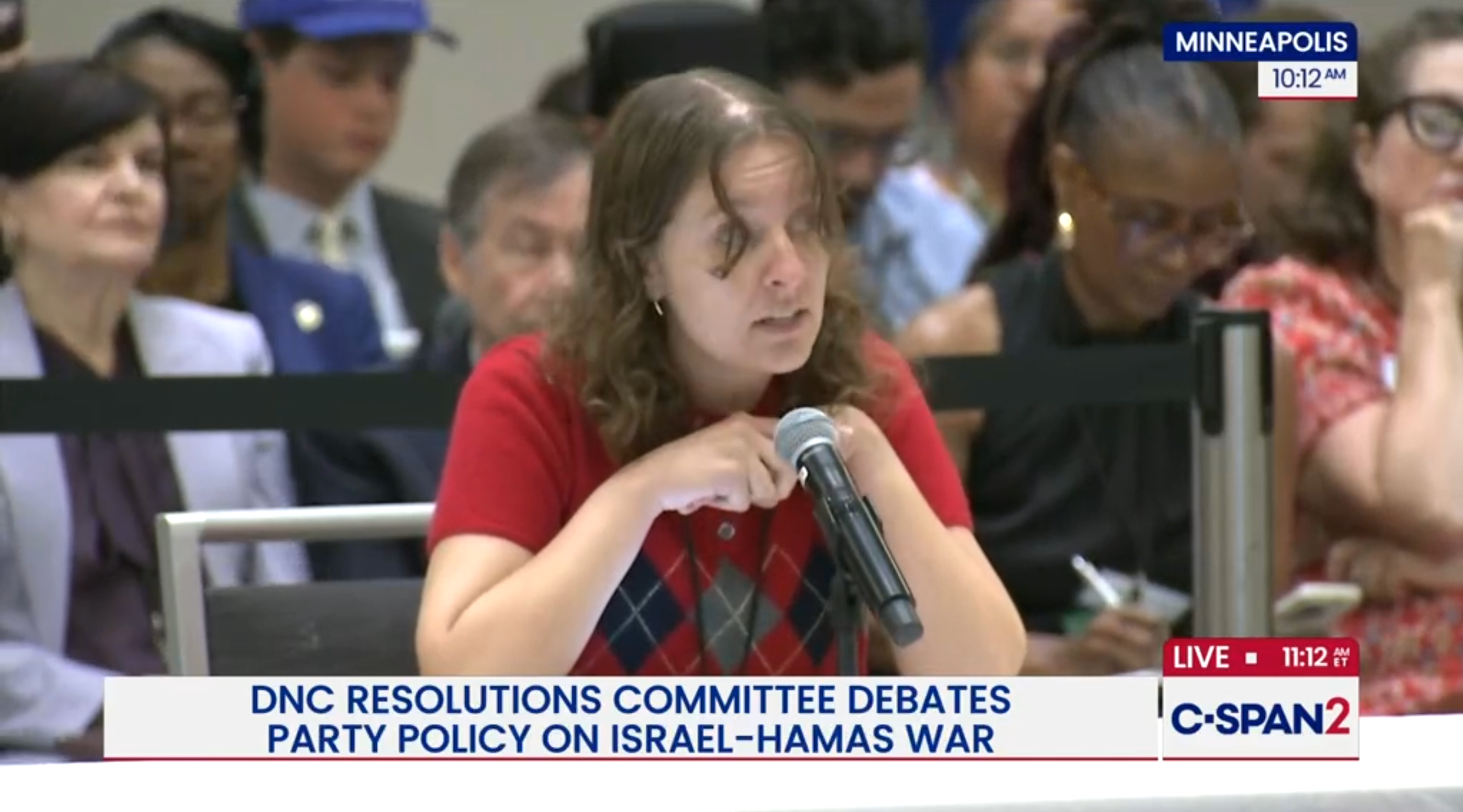 A photo of Allison Minnerly speaking into a microphone on C-Span.