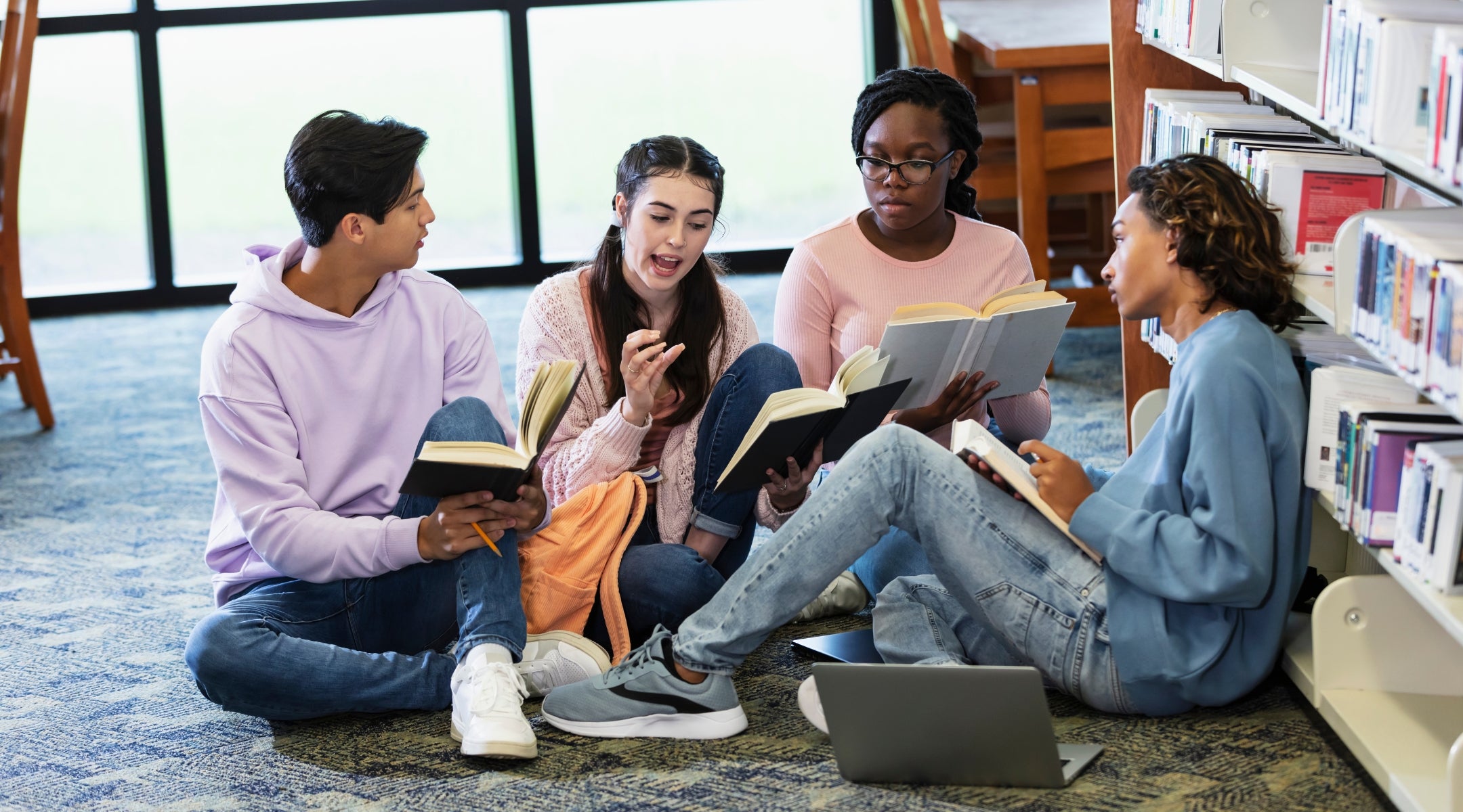 Four teens on the floor of a library