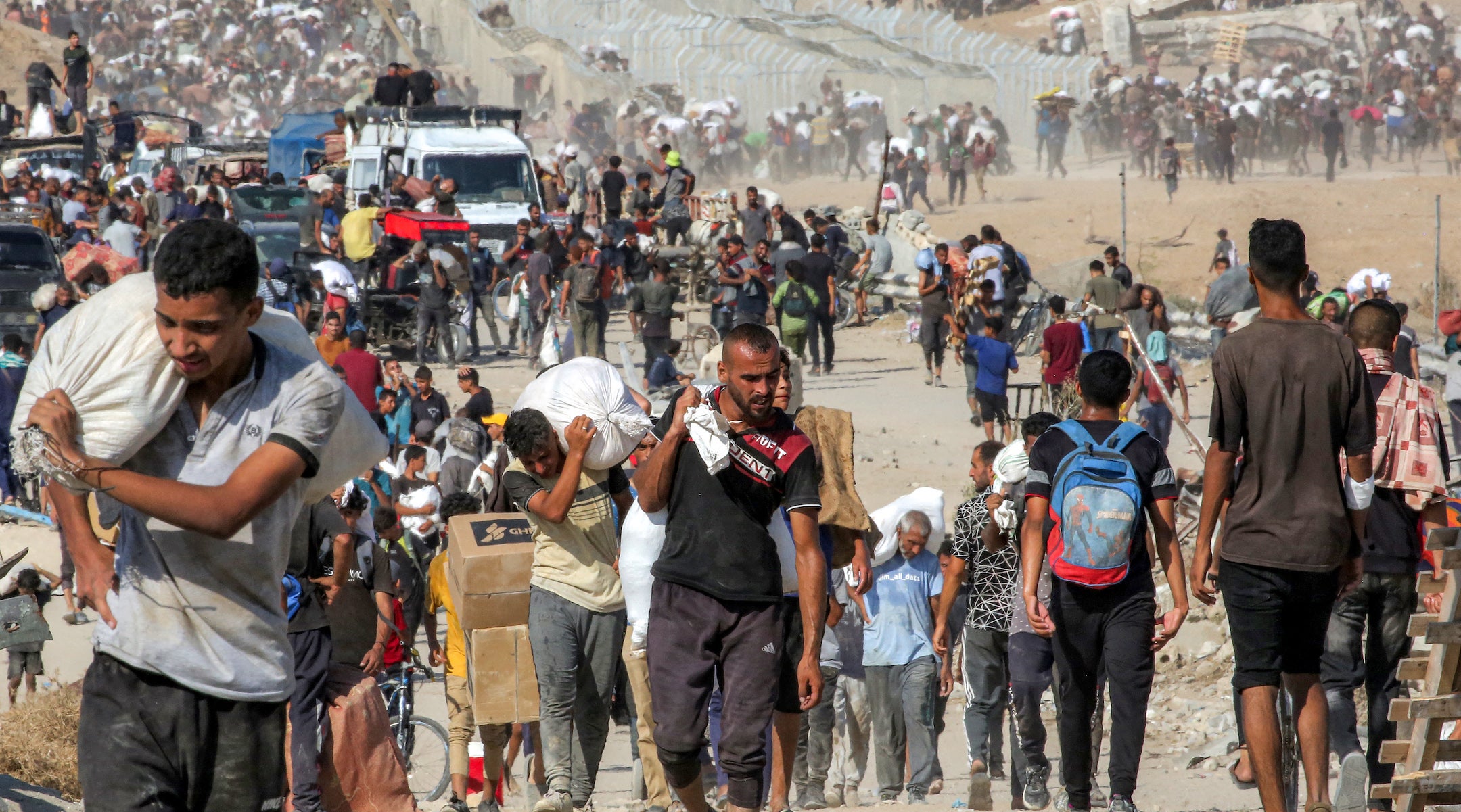 Palestinians in Gaza walking with bags of aid