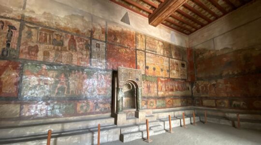 A photo of the Dura-Europos Synagogue wall paintings in the National Museum of Damascus. The frescoes depict multiple biblical stories and have a sheen from the lacquer coating.
