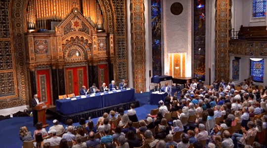 A photo of the mayoral candidates in B’nai Jeshurun surrounded by congregants in the pews.