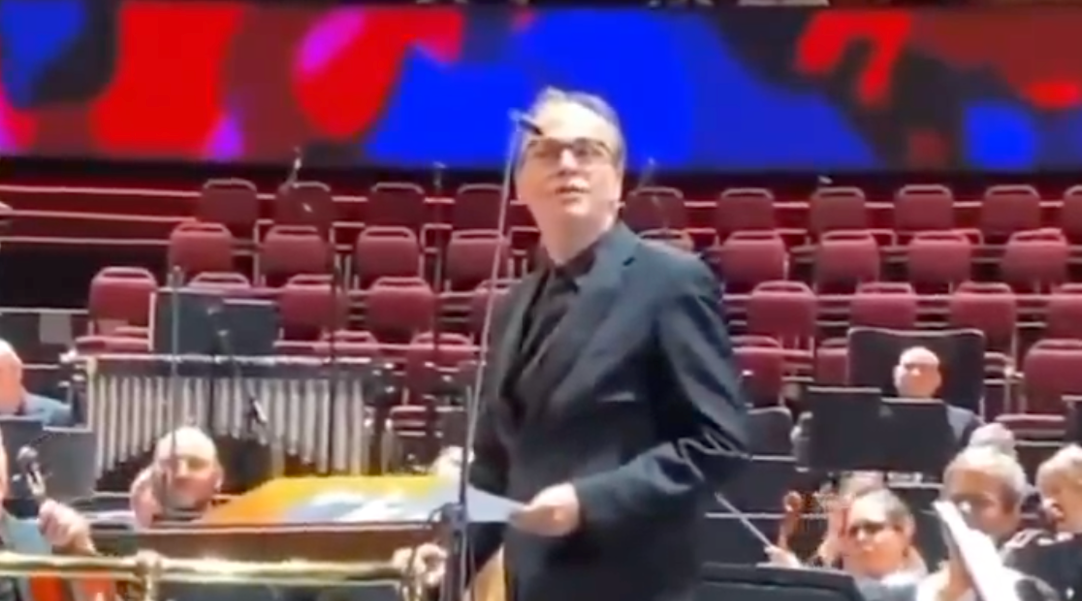 Israeli conductor Ilan Volkov speaking at a concert from a white sheet of paper.