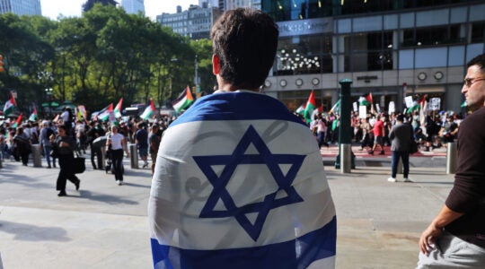 A photo of a man wearing an Israeli flag across his back in the street.