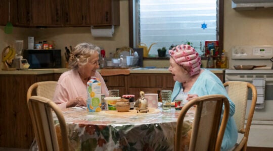 A photo of Rita and June sitting at a table in their pajamas.