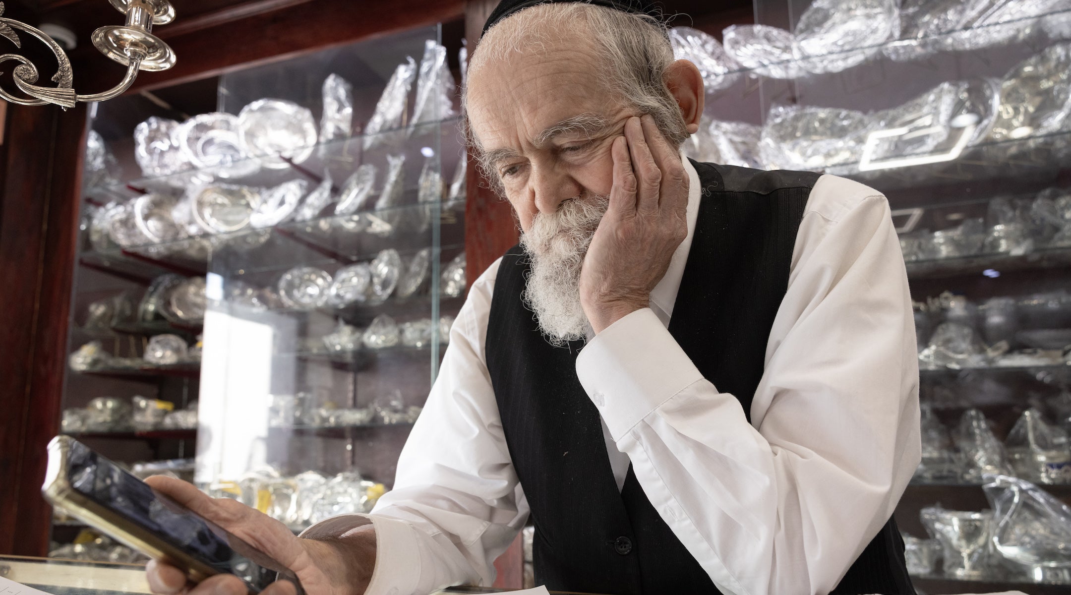 A Hasidic man looks at a phone.