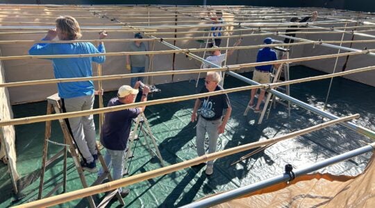 Men work t construct a sukkah.