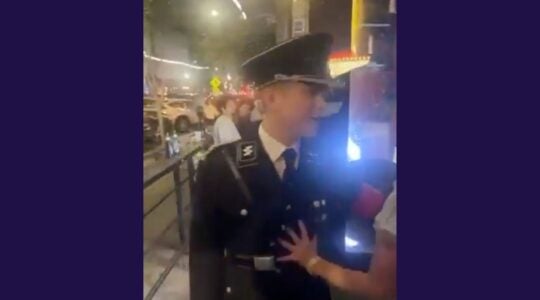 A man wearing a nazi uniform is pushed by a hand off camera.