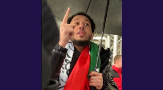 A photo of Bazrouk wearing a keffiyah and pointing.